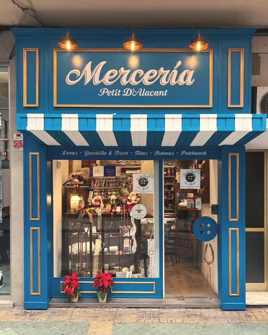 Fachada de Miss Gofre en azul pastel, con rótulos enmarcados en rosa y blanco, toldo rosa y mostrador abierto.