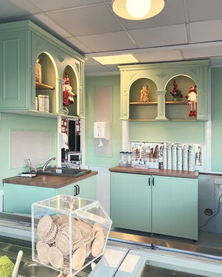 Mobiliario comercial vintage en verde menta, con vitrinas de arcos, molduras decorativas, estanterías y mostradores a medida.